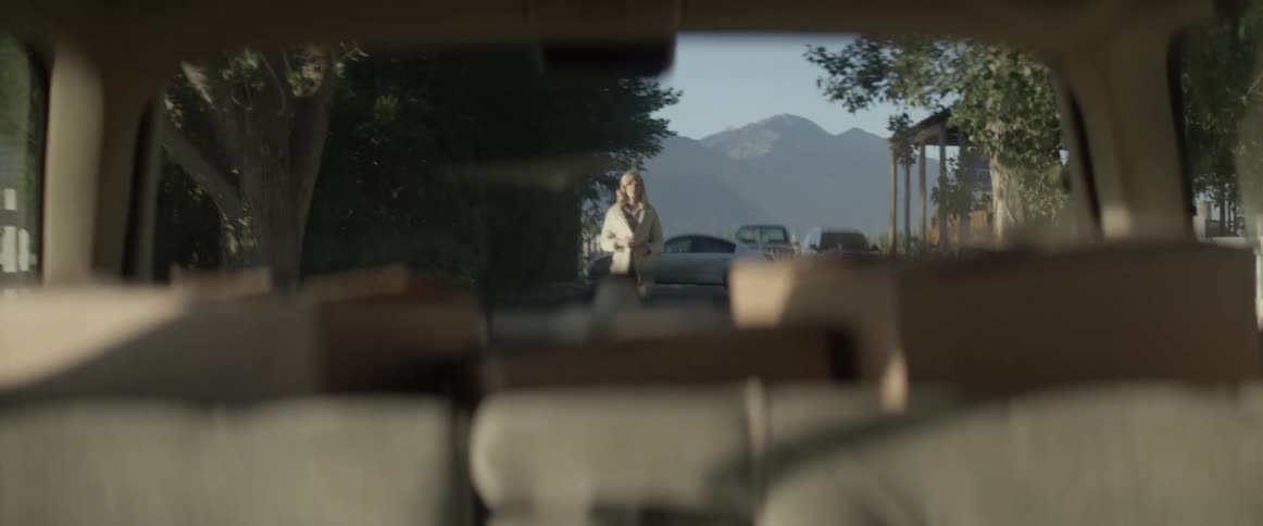 A woman watches as a car drives away