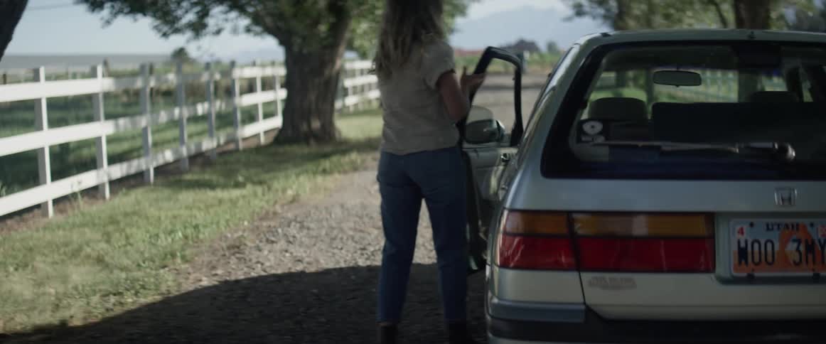 A white woman walks to her car and gets into the drivers seat