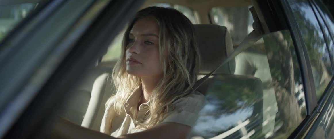 Young woman driving car wipes away tears from eyes