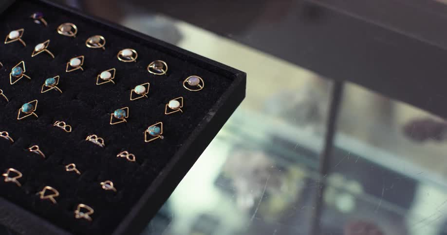 Hand places ring into display tray of costume jewelry rings