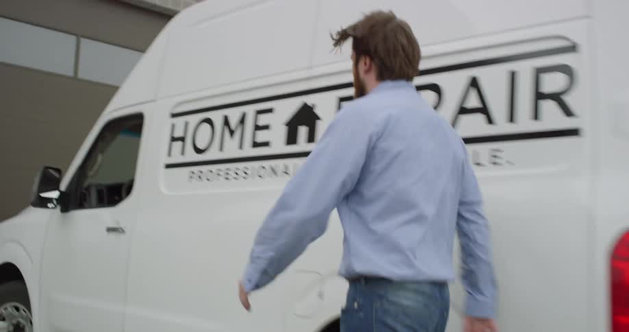 An employee climbs out of a work van and gets into the drivers seat