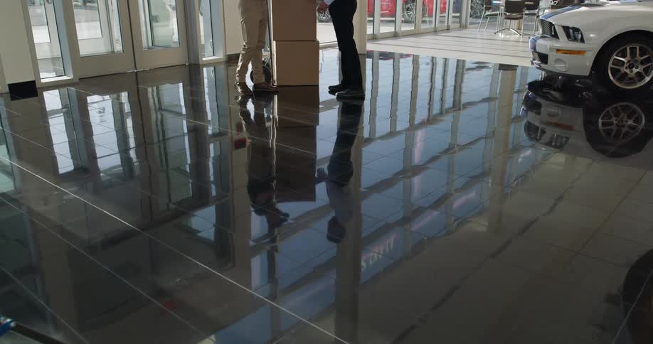 Reflection of package being delivered at dealership and man signing for it