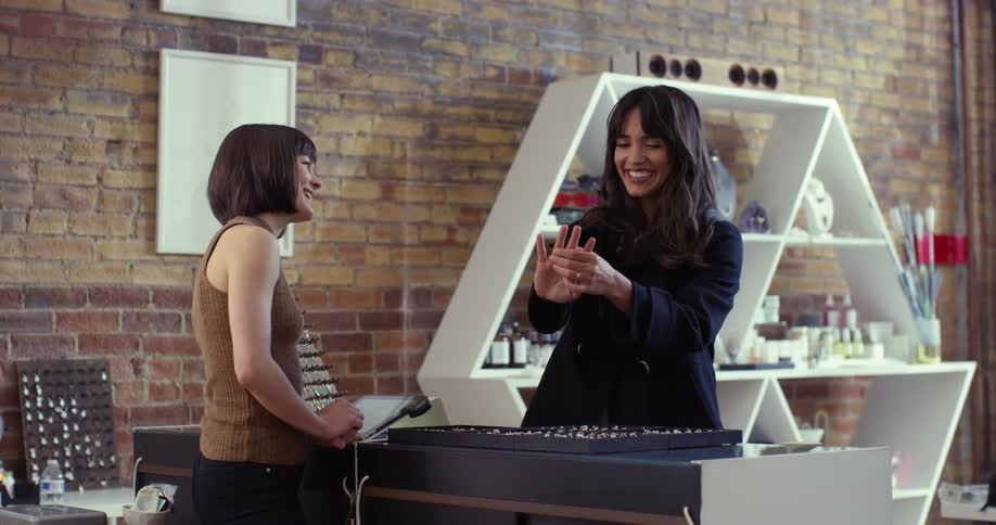 A woman tries on a ring in a store with another woman employee