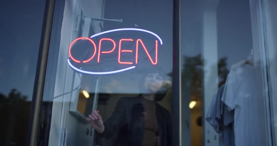 A woman turns on the open sign