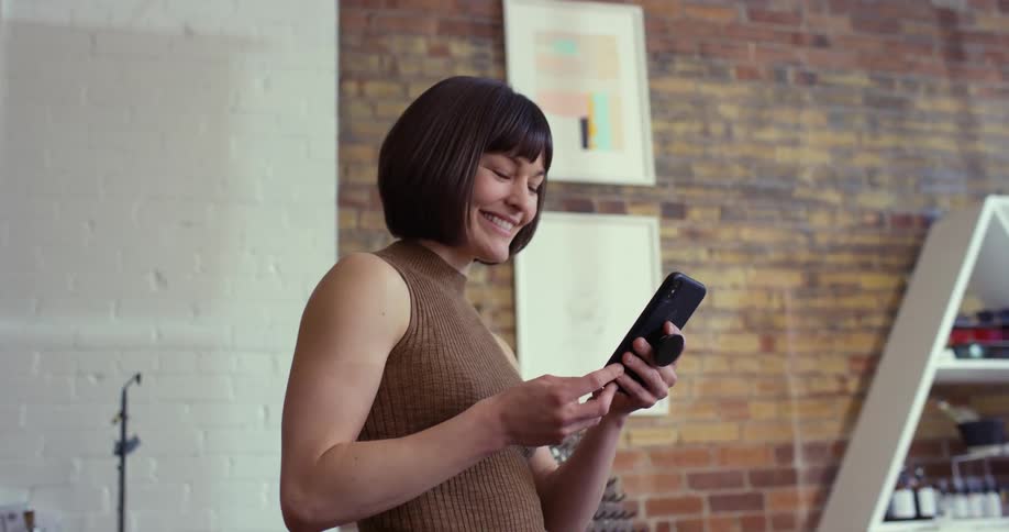 Woman at store counter picking up cell phone and smiling
