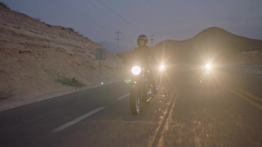 Three motorcyclists travel down a road running through a desert