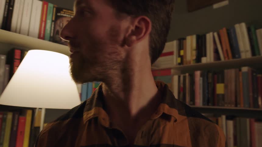A bearded white man in a library turns around suddenly
