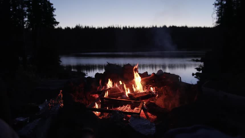 A campfire with a lake in the background