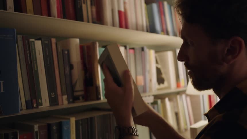 A man pulls a book off a shelf in a library