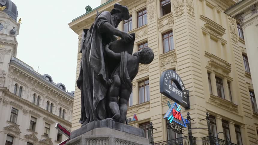A statue sits on a fountain in the middle of a downtown city area
