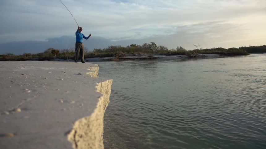 A man fishing from a seawall