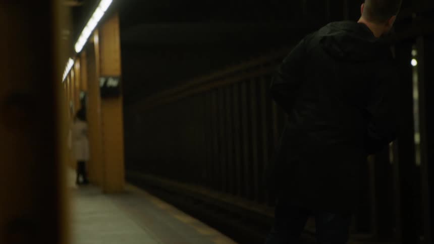 Man waits in dimly lit transit station