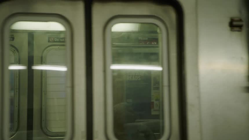A subway car with several passengers moves through a subway station