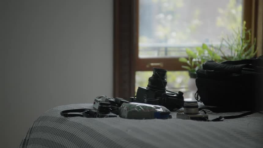 A person walking in a bedroom with camera equipment on the bed