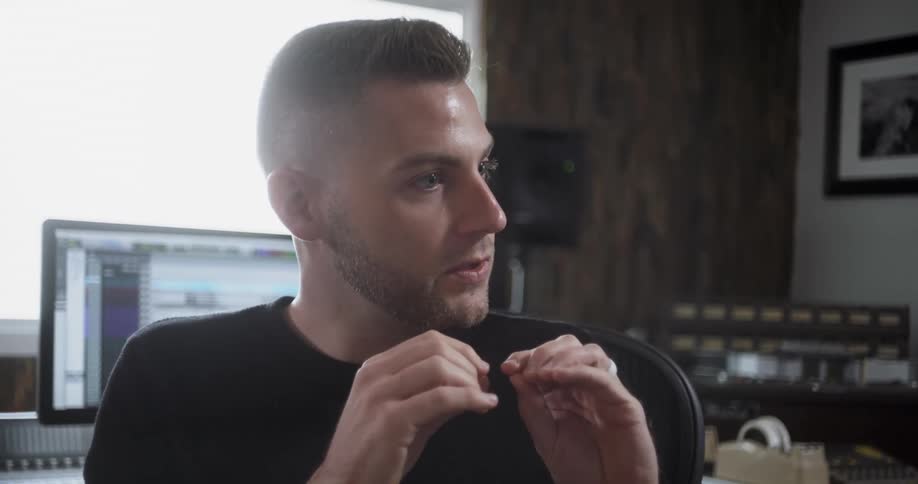 A man in a recording studio talks with someone