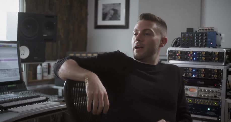 A man in a recording studio sits in his chair and talks