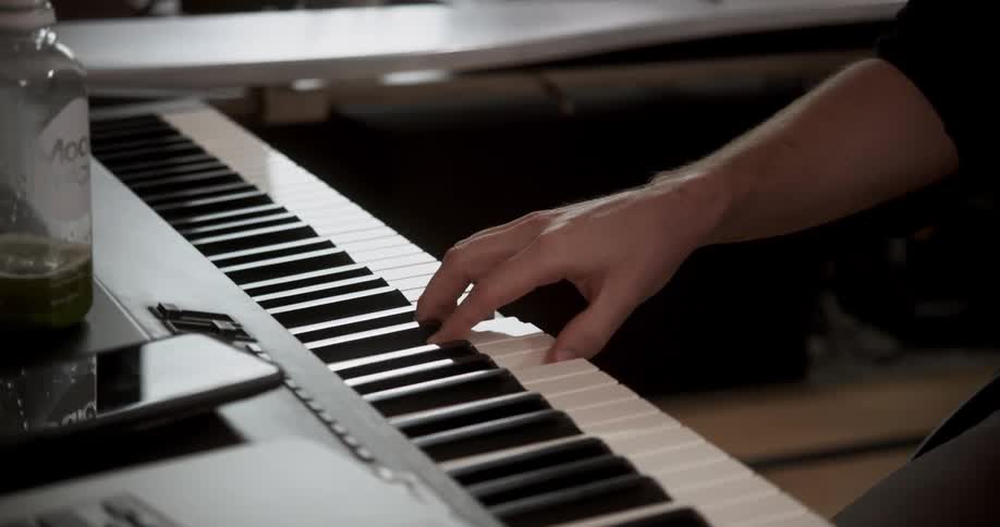 A musician sits in a studio and plays the piano