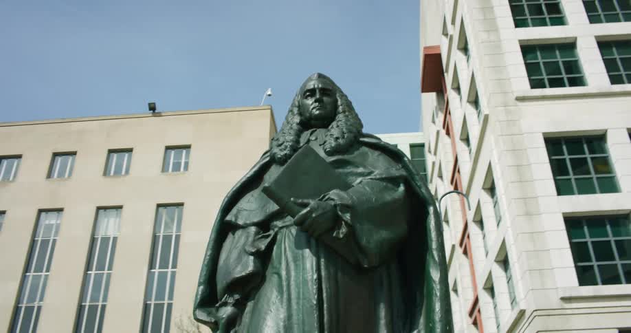 A statue stands outside several tall buildings