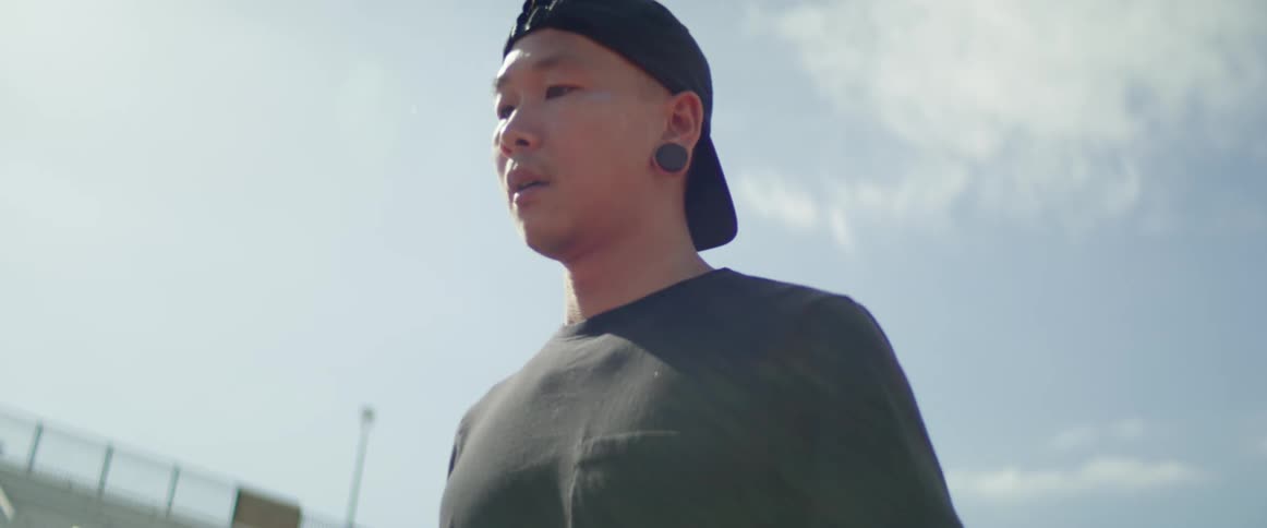 An asian man walks around an outdoor stadium