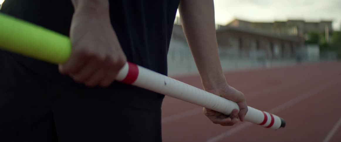 A teenager holding a pole gets ready to run on a track
