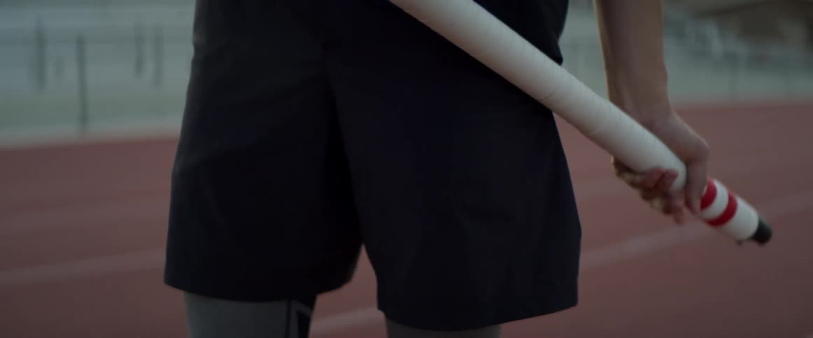 A male athlete holds a pole while standing on a track