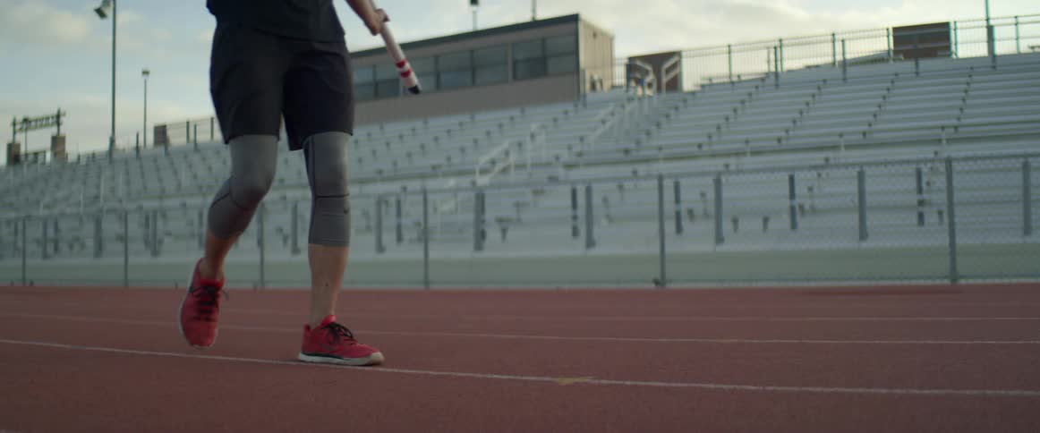 A pole vaulter walks along a track outdoors