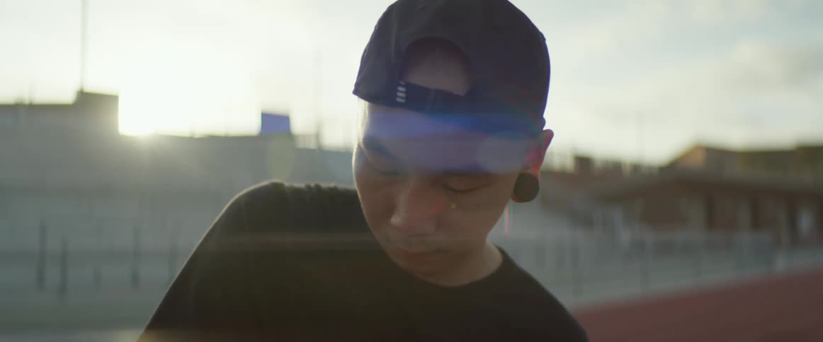 An asian man stands in a stadium and looks into the distance