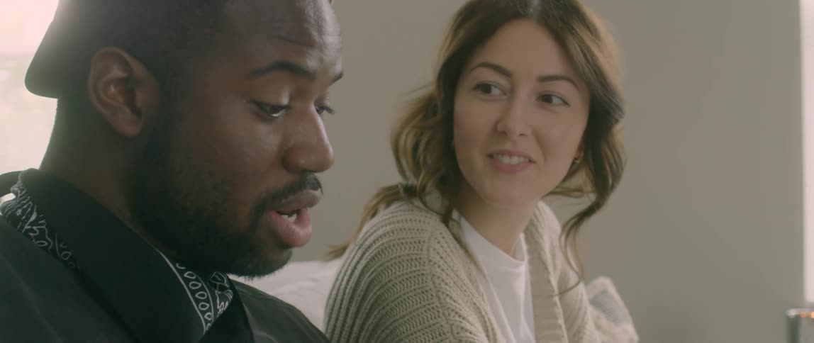 A man and woman are talking and sitting on a couch