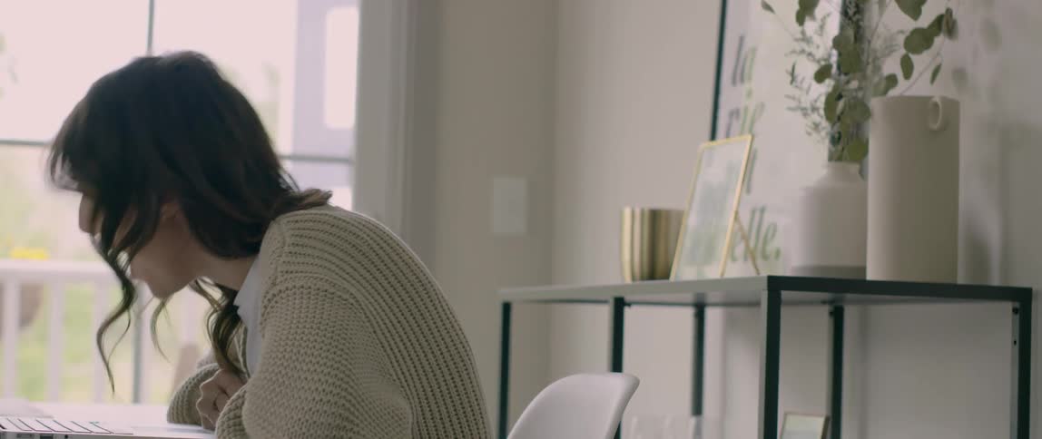 A woman sits inside a room and laughs