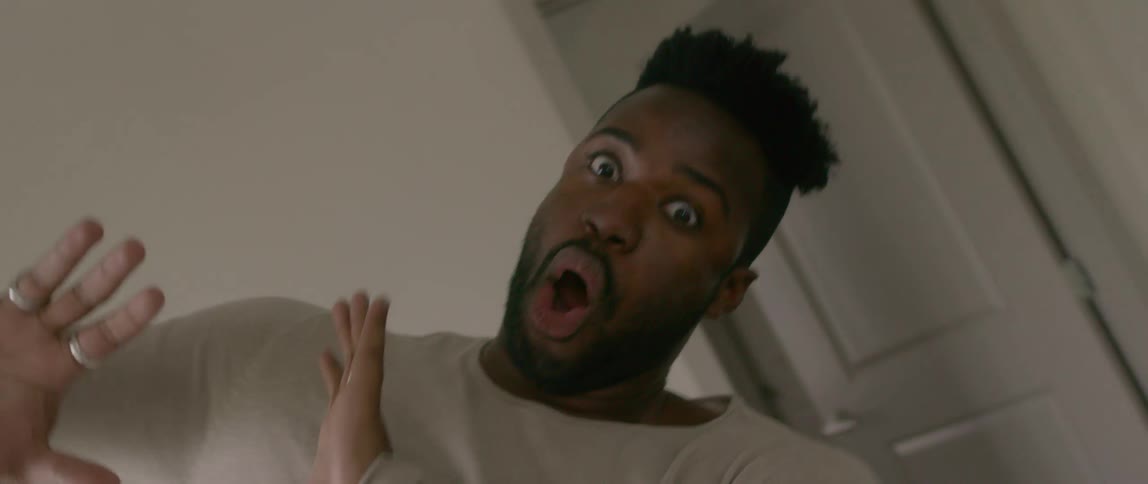 A black man strikes several poses while standing in a room