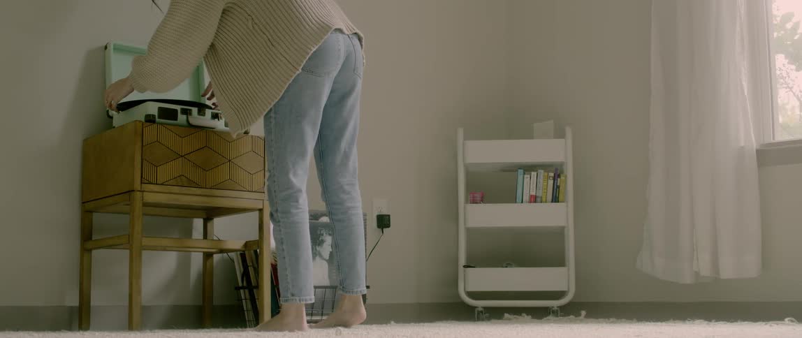 Woman places record in record player and sets needle