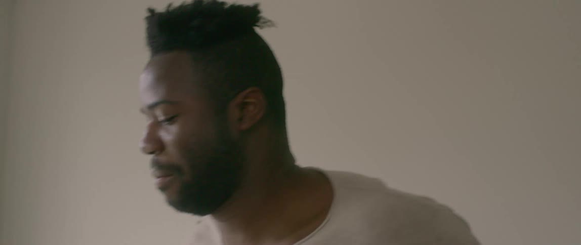 A black man dances in a room in his bare feet