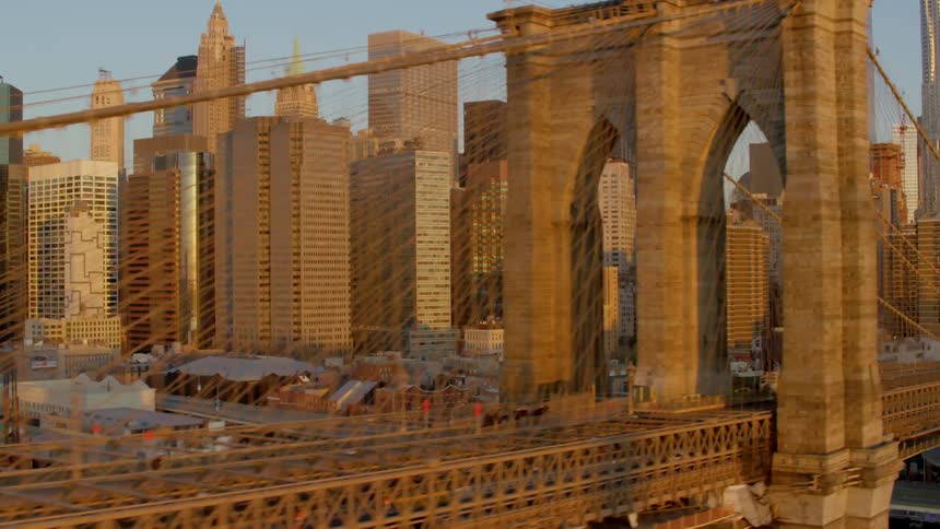 Brooklyn bridge in front of new york city skyline at sunset