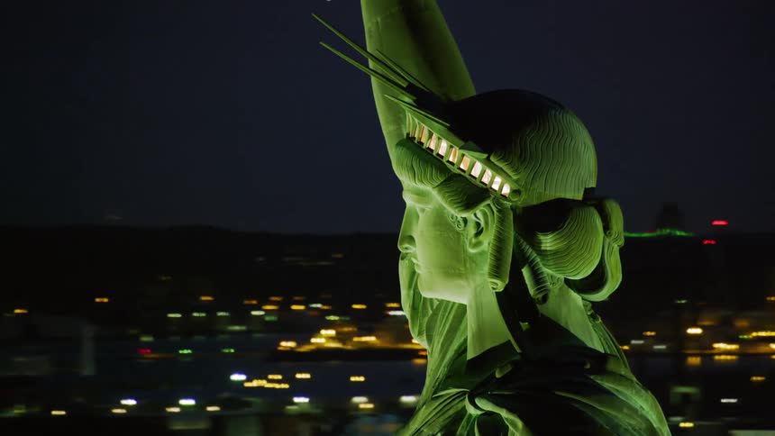 Close up of the statue of liberty with the lit up city skyline in the background
