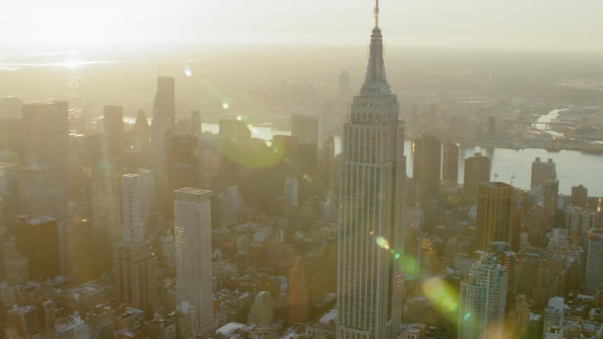 Sun casts glare from horizon backing river and buildings surrounding the empire state building