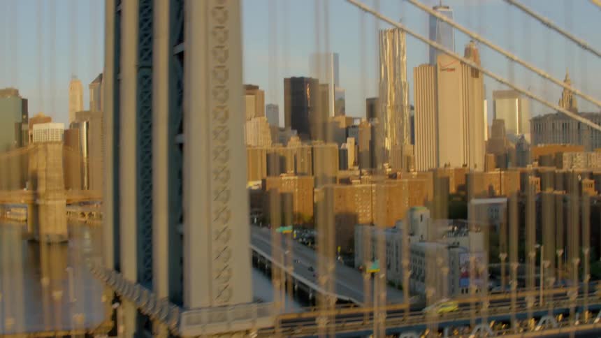 Cars cross suspension bridge with downtown skyline in the background