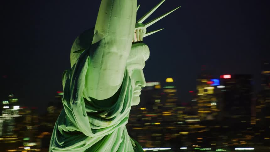 Close up of the statue of liberty with city skyline lit up in the background