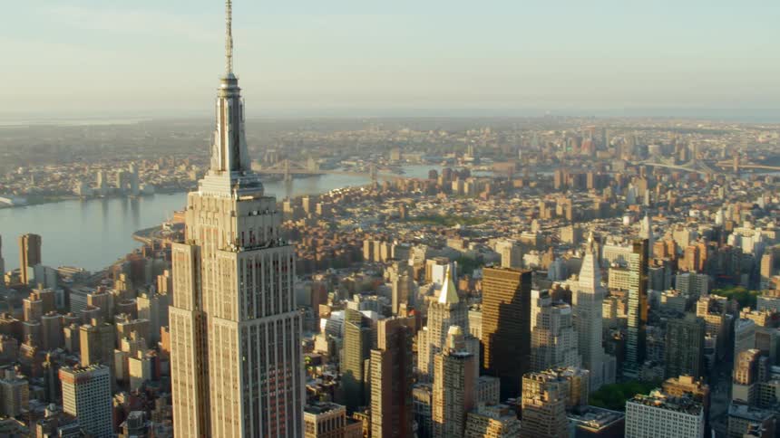 A skyscraper with a tall steeple towers over a vast downtown urban area