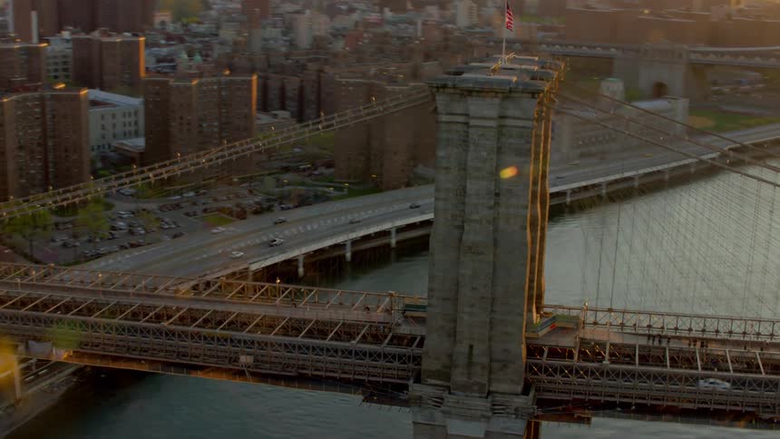 Sun highlights buildings and glares off river near suspension bridge