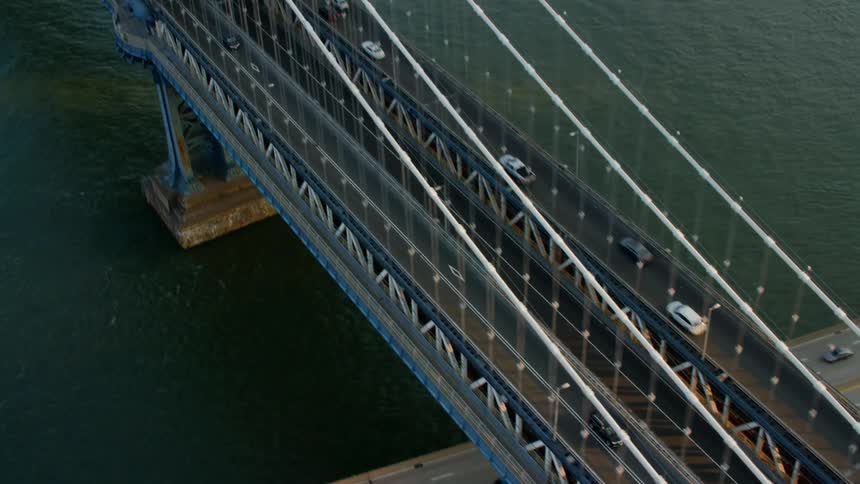 A bridge with vehicles on it with the city skyline in the background