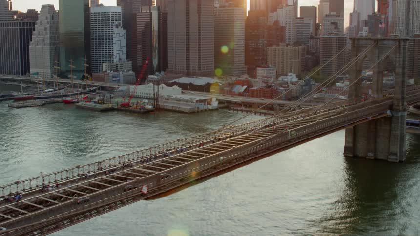 Cars drive across a suspension bridge and into the city
