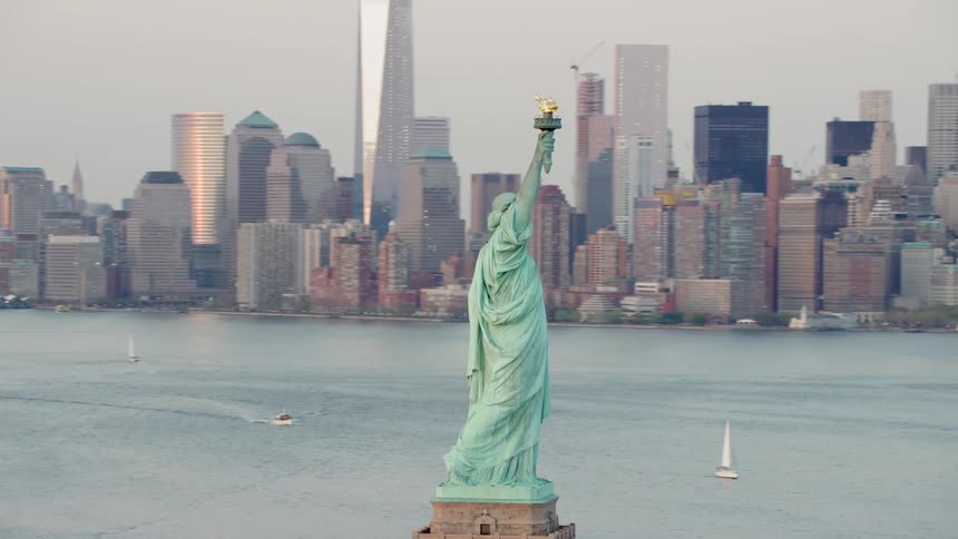 Boats in the water going past the statue of liberty