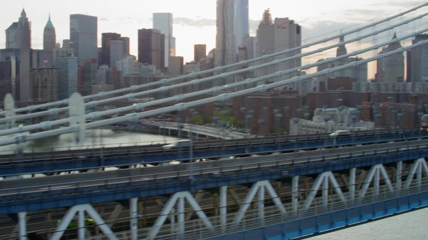 Vehicles driving across a bridge with the city skyline in the background