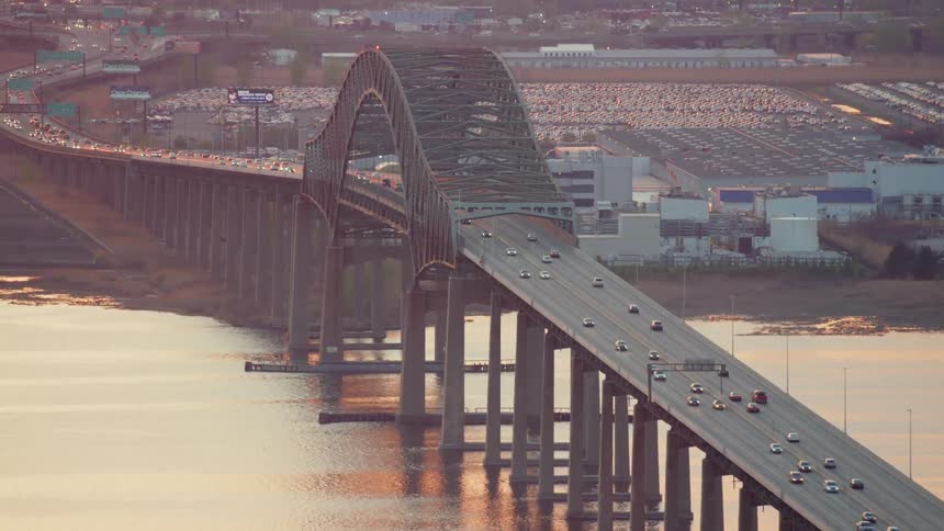 An aerial view of cars driving over a city bridge at sunset