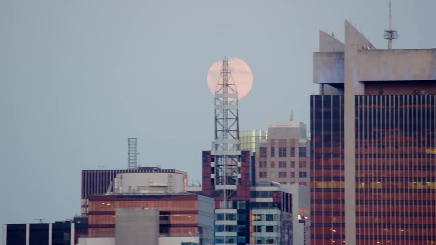The moon above buildings in a city