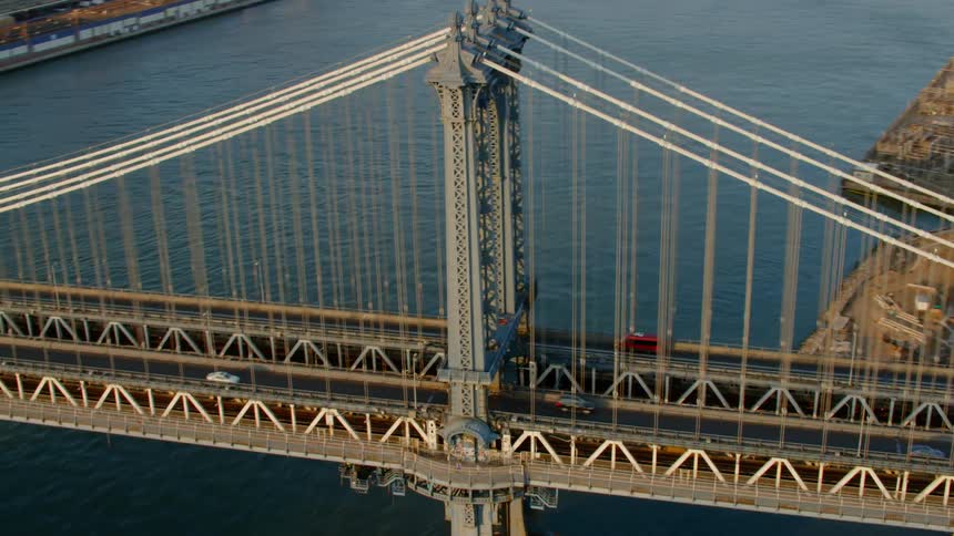 Cars travel on the bridge over the river next to the city