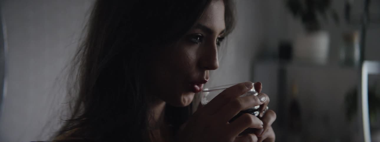 A woman lifts a steaming cup to her lips and takes a sip
