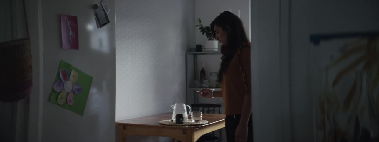 Woman makes tea in dimly lit kitchen