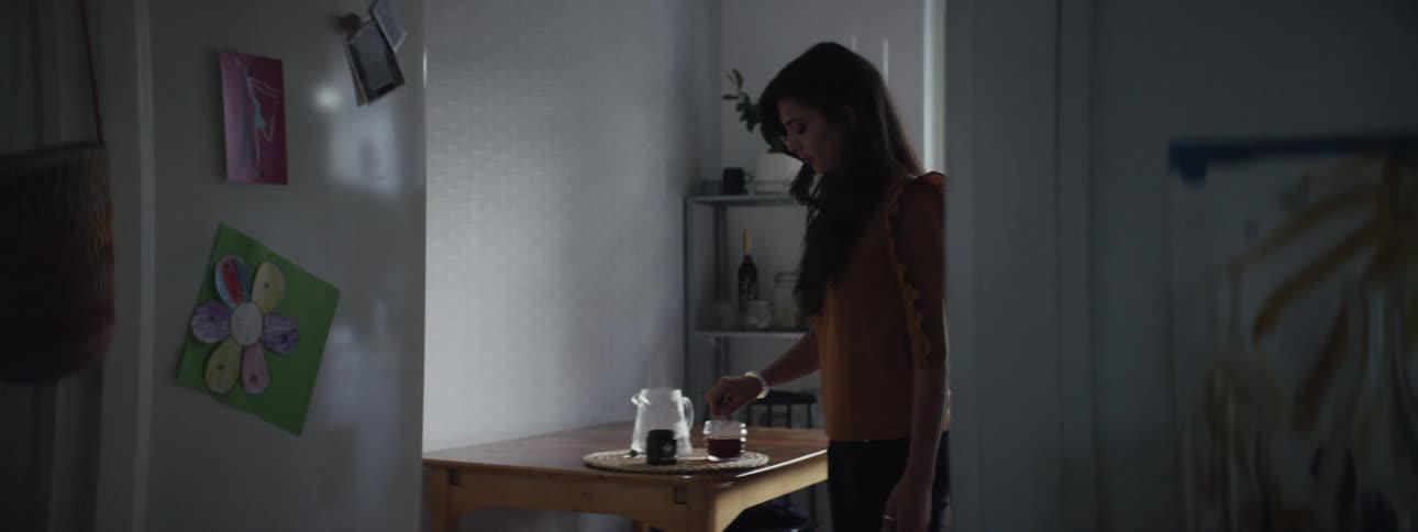 Woman stirs tea at table in kitchen