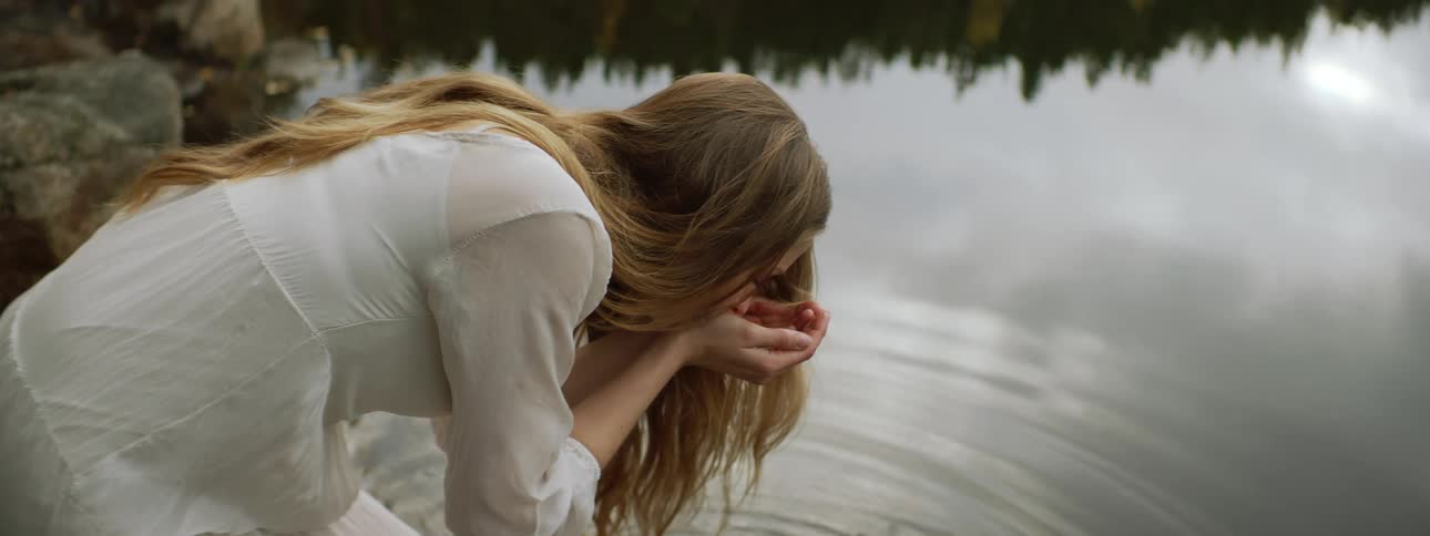 A woman drinks from the lake